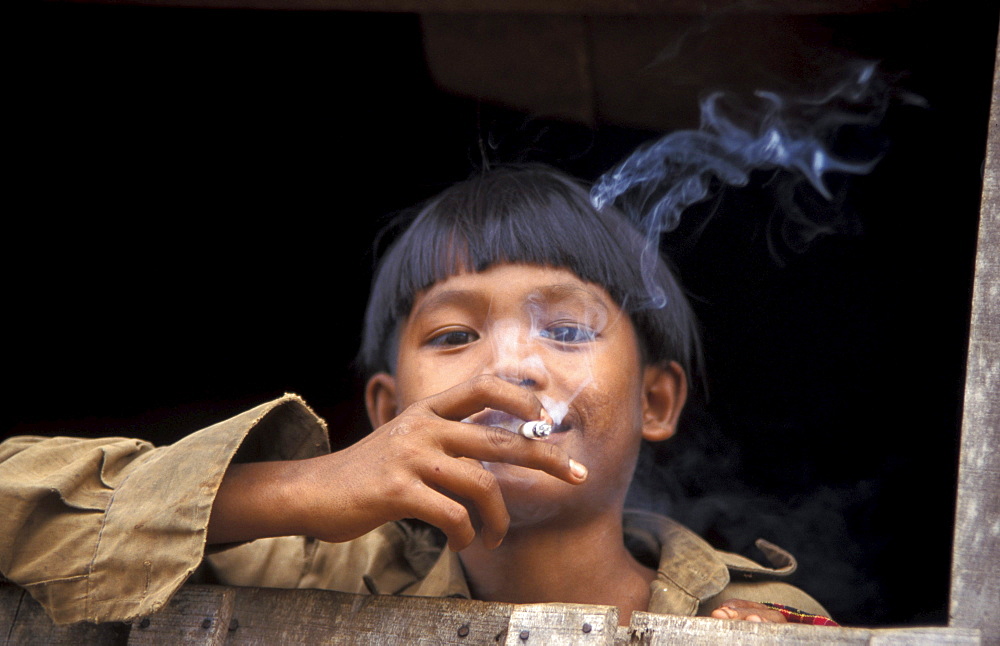 Cambodia boy smoking a cigarette. Malik village. Ratanakiri.