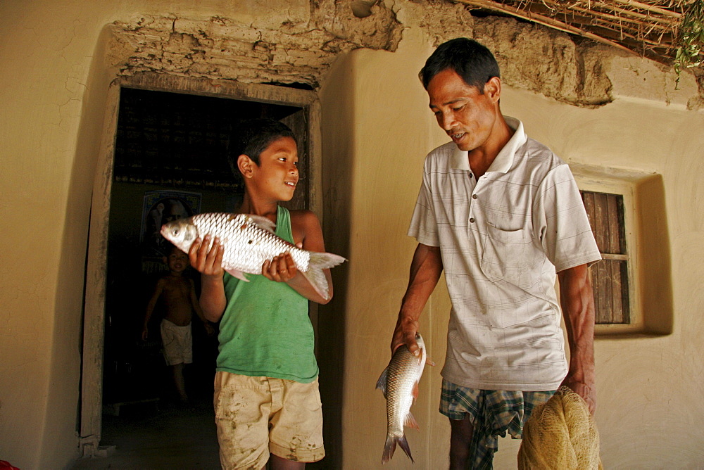 Bangladesh farid pathang and homar, father and son of garo tribal minority, with freshly caught fish, haluaghat, mymensingh region