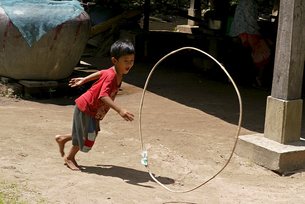 CAMBODIA Nat Sokatt (4), son of Sovat Komsonath and Say Choun, playing with hoop, Ban Bung village, Stung Treng district