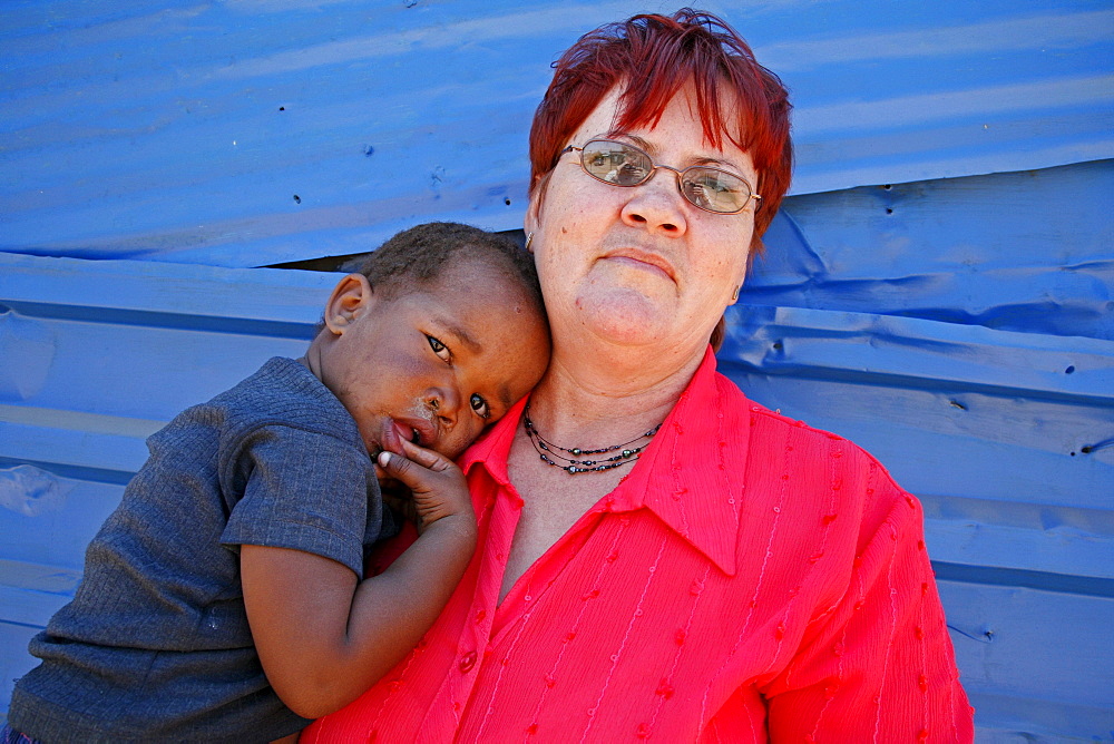 Namibia woman with a child standing beside a -school building, rehobeth