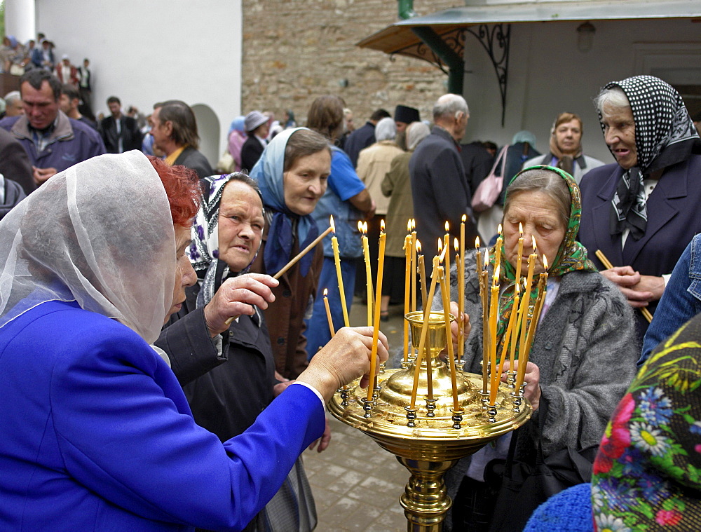 Russia lighting candles at pechersky caves monastery, pskov district, founded on august 28th 1473 by saint jonah sheshnik