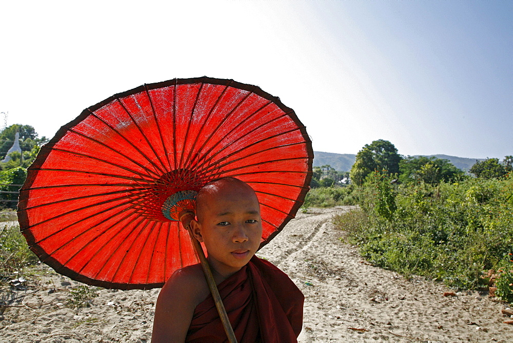 Myanmar monk with sunshade at white stupa, mingun, near mandalay 