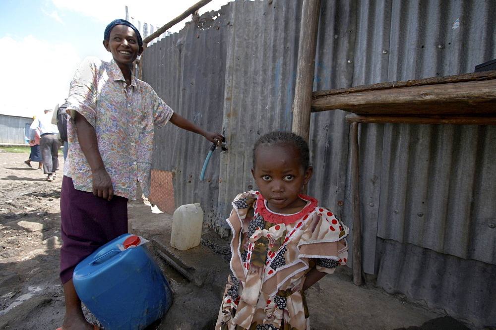 Kenya. Woman collecting water from public tap in mukuru ruben, a slum of nairobi