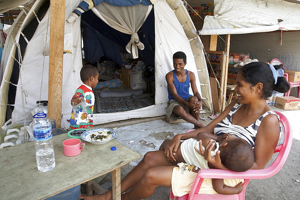 East timor. Family in front of their tent at the camp for internally displaced people (idps) located at the police academy in dili