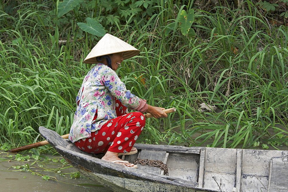 Vietnam scene in vinh long: woman paddling boat on backwaters