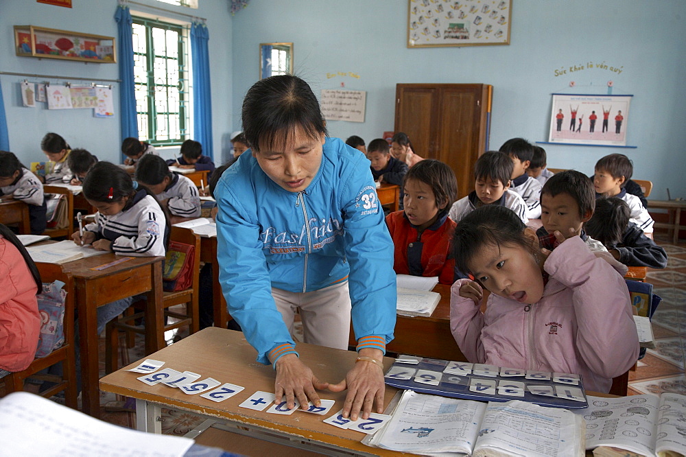 Vietnam yen mo tu commune primary school, ninh binh province. this is one of several schools in this region of northern vietnam where crs in cooperation with the local education authorities has implemented inclusive education practices, whereby children with mental or physical disabilities are integrated into the normal primary schools. crs provides special training for the teachers to help them. the image shows 13-year-old pham thi bich ngoc (in pink jacket) who suffers from cerebral palsy and is intergrated into a class of 11-year-olds. her teacher nguyen thi mund is seen here helping her with an alphabet exercise