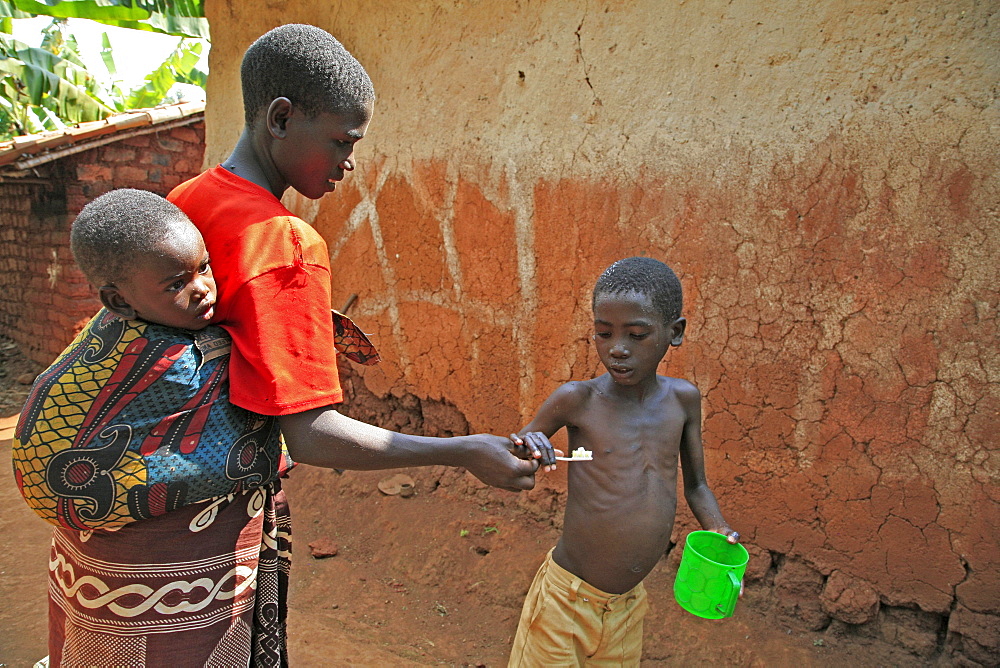 Burundi family of speciose ciza (32) and three children, claude (9), constantin (6) and orave (1). Claude brushing his teeth. Gitera.