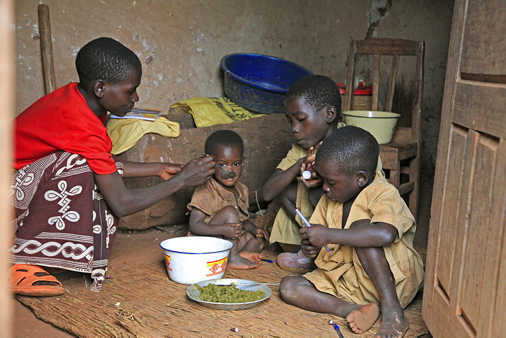 Burundi woman feeding her children, gitera.