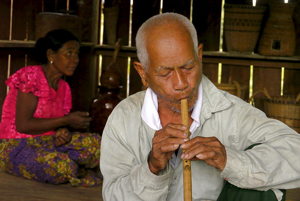 CAMBODIA Katot village, inhabited by the Prov tribal group, Stung Treng district. DPA cultural centre built by DPA and financed by SCIAF. Village elder, Nom Boun (79) playing his flute