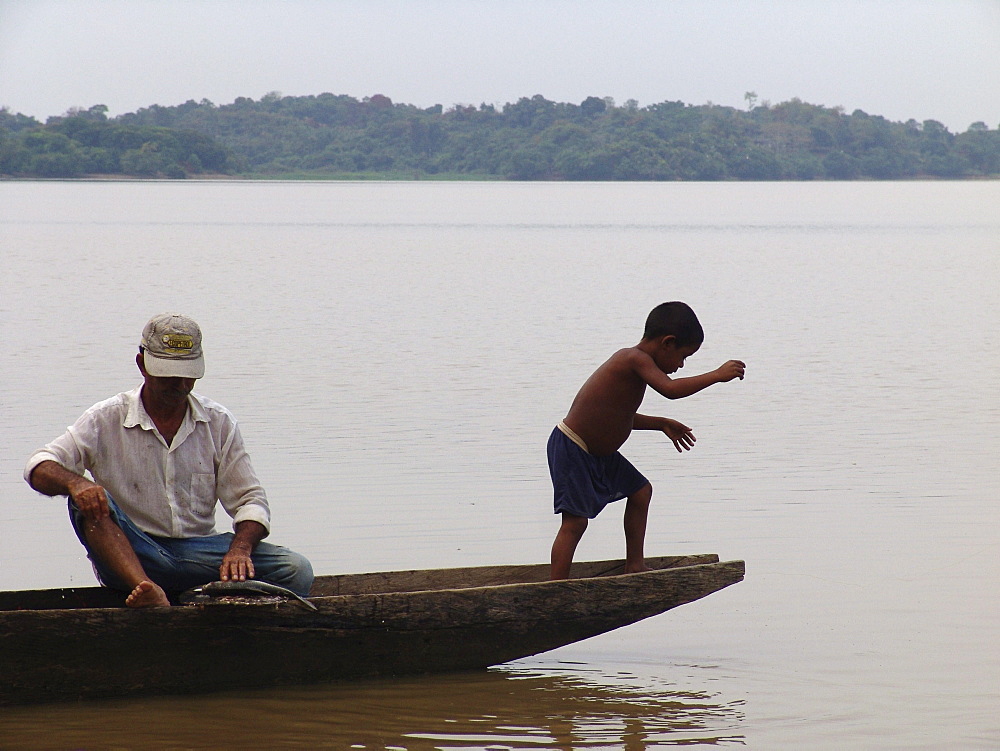 Colombia boy fishing from a dugout canoe in the rio magdalena, barrancabermeja