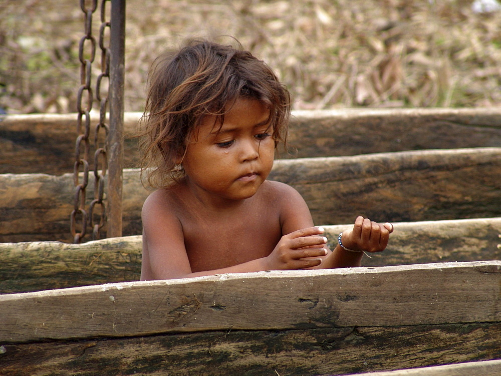 Colombia child sitting in a dug out canoe besdie the rio magdalena, barrancabermeja