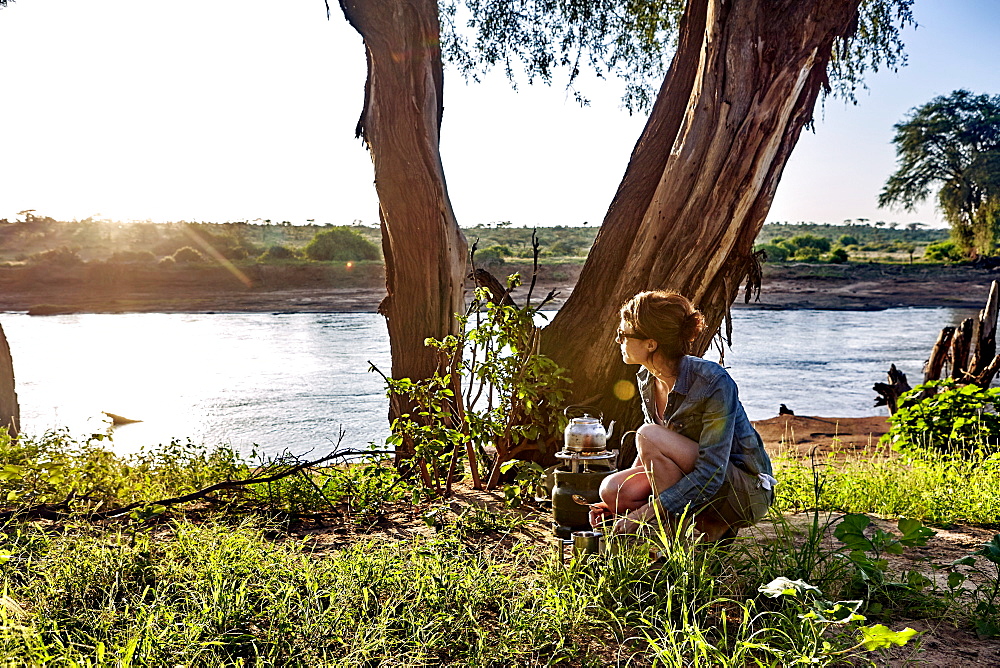 A young woman observes the early morning light while camping in Samburu National Park, Kenya, East Africa, Africa