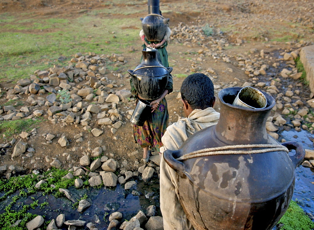 Women fetching water early in the morning. The wells in this area are empty during the dry season,forcing women to walk very long distance to fetch water in the nearest river bed. Ethiopia