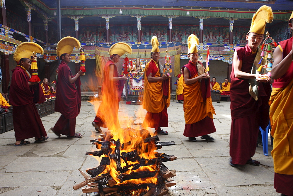 Fire ritual at chiwang monastery during the mani rimdu festival. these monks circumambulate the pyre after its ignition. one holds a long book wrapped in a felicitous scarf. the purifying fire takes the offering and raises them towards the sky in smoke. the circumambulatory ritual also recalls the way disciples showed respect for the buddhas body. solu khumbu, nepal