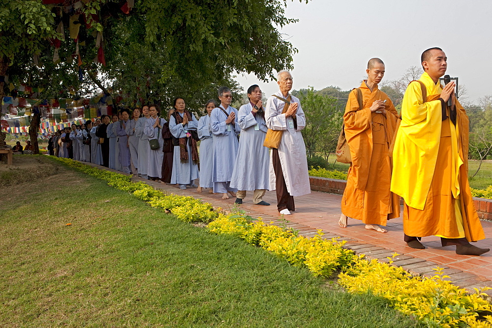 Buddhist pilgrims circumambulate the mayadevi temple and the pond in front of it. Lumbini, nepal