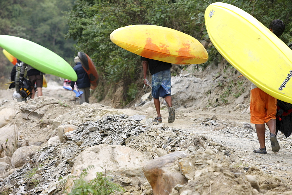 Paddlers carry their kayak to the start point for Downriver challenge. Paddlers race from a Le Mans style mass start, head to head down a stretch of challenging class 4 whitewater. Trisuli, Nepal