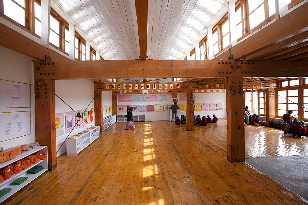 A light-filled elementary classroom. A white ceiling reflects light from the windows above. Traditional building methods and materials, such as the poplar and willow ceilings are combined with modern solar and passive solar technology. Druk Padma Karpo Institute. Shey, Ladakh, India