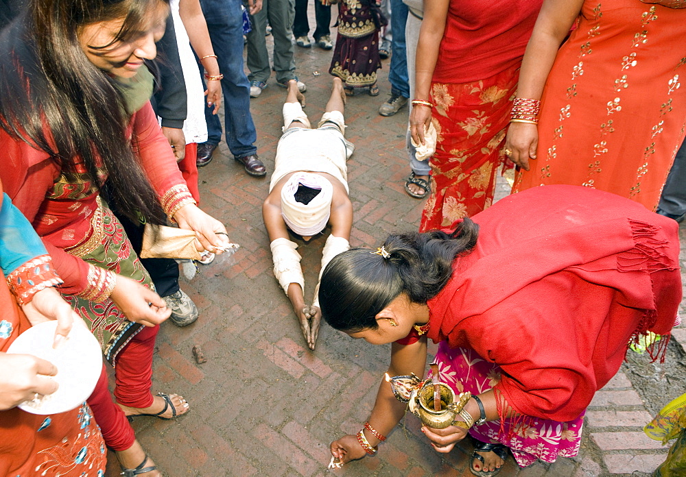 Some religious people reach Brahmayani temple measuring their body length. To do so, a person prostrates on the ground and extends his clasped hands above his head. An assistant puts a few grains of rice at the end of the clasped hands as a marking point. Then, the man steps to this marking point and then prostrates again. Bhaktapur, Nepal