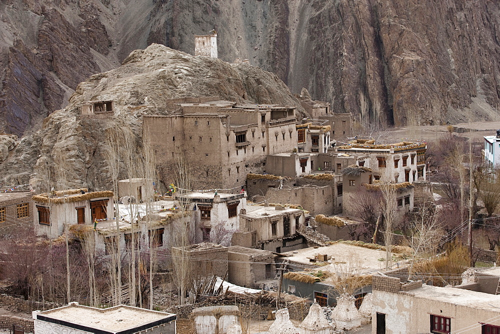 The 400 year-old stone and mud brick house of the Lunpo Alchi (minister of Alchi village) towers above farmhouses topped with fodder, and sits below a latho (god place) marking the presence of a local god. Ladakh, India