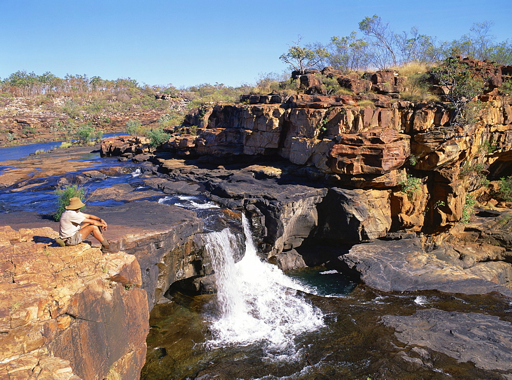 A man sitting on a rock up river, at the first stage of the Mitchell Falls in Kimberley, Western Australia, Australia, Pacific