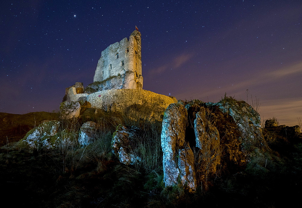 View of rocks and Mirow Castle ruins illuminated at night, Polish Jura, Poland, Europe