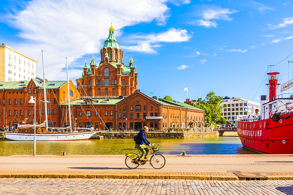 Uspenski Cathedral and cyclist by harbor in Helsinki, Uusimaa, Finland, Europe