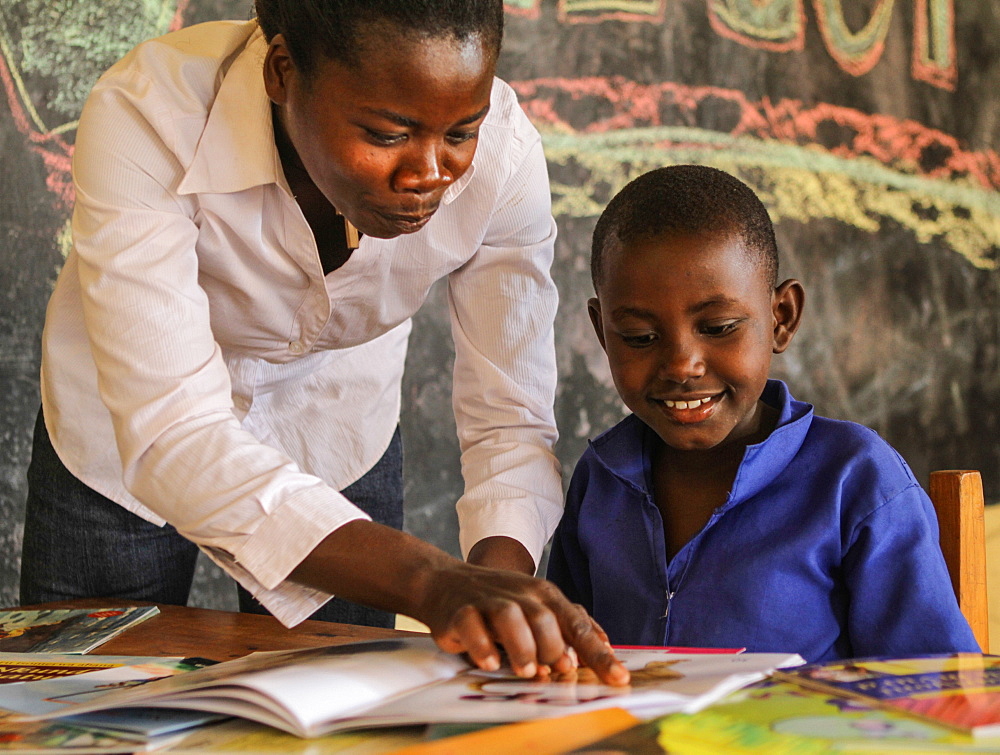 Alice Isingizwe 8 years old who is dumb and her teacher Musabyemariya Alphonsine from Ngwino Nawe, the village for children with disability, teaching Alice how to read a book using signs, Rwanda, Africa