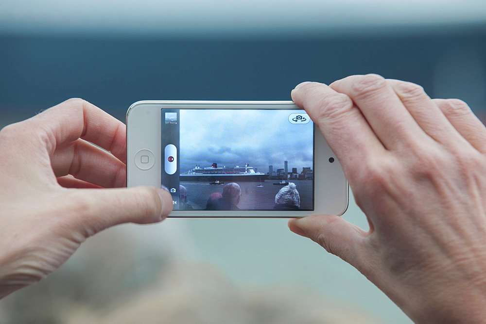 Hands photographing a Cunard cruise ship with an iPhone, United Kingdom, Europe