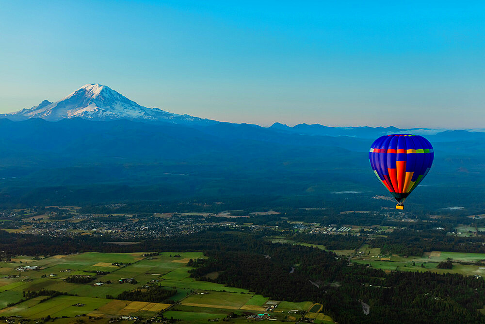 Aerial view of hot air balloon floating over farmland and Mount Rainier in the distance, Washington State, United States of America, North America