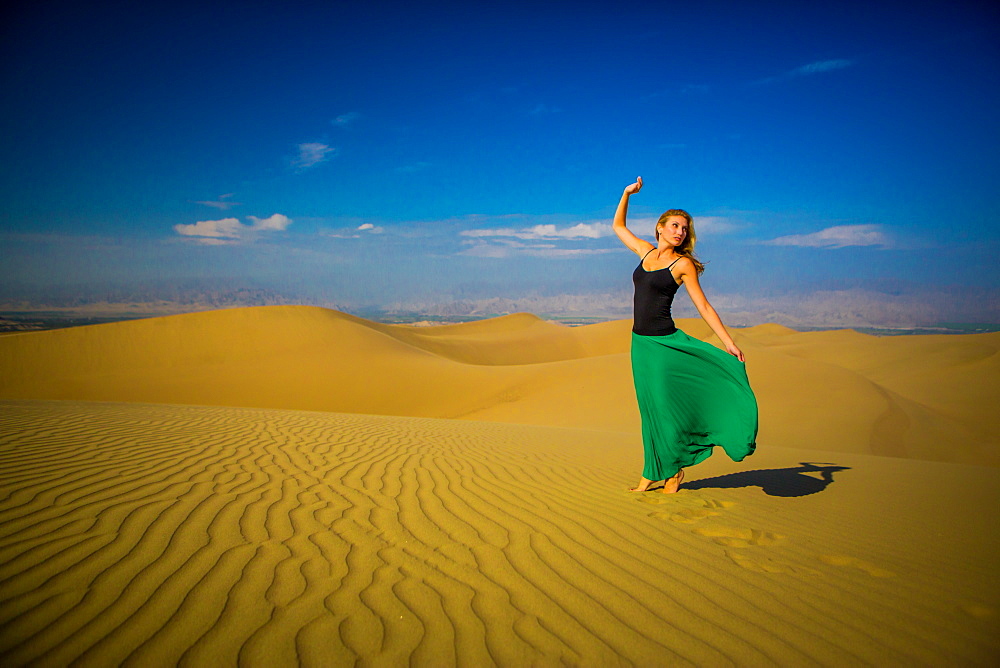 Woman standing on sand dune, Huacachina Oasis, Peru, South America