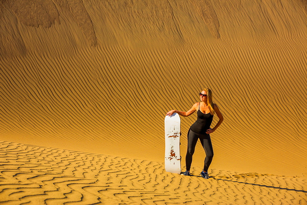 Woman sand boarding on sand dune, Huacachina Oasis, Peru, South America