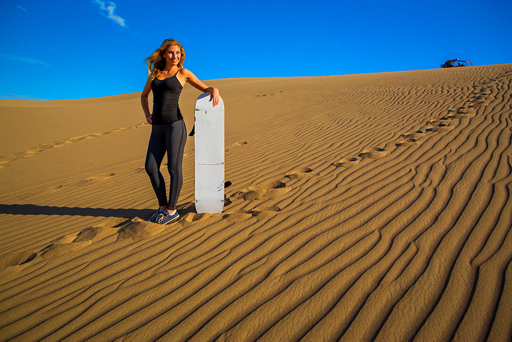 Woman sand boarding on sand dune, Huacachina Oasis, Peru, South America