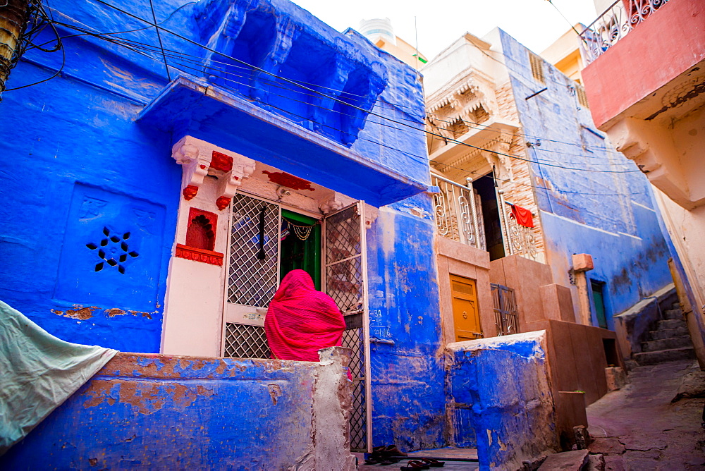 Woman standing in front of her blue house in Jodhpur, the Blue City, Rajasthan, India, Asia