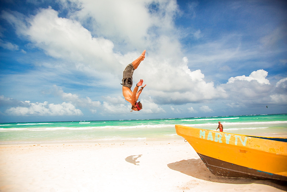 American Ninja Warrior Acrobat, Travis Brewer, does a back flip off a boat in Tulum, Mexico, North America