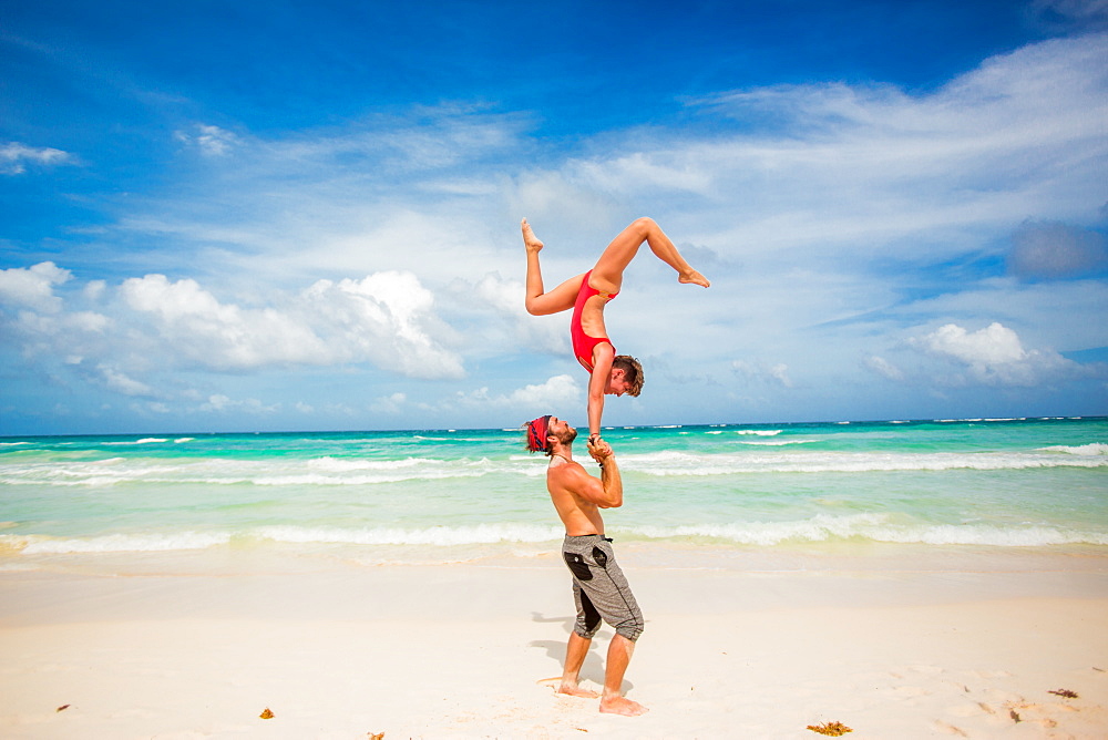 Acrobatic couple balancing together on the beach of Tulum, Mexico, North America