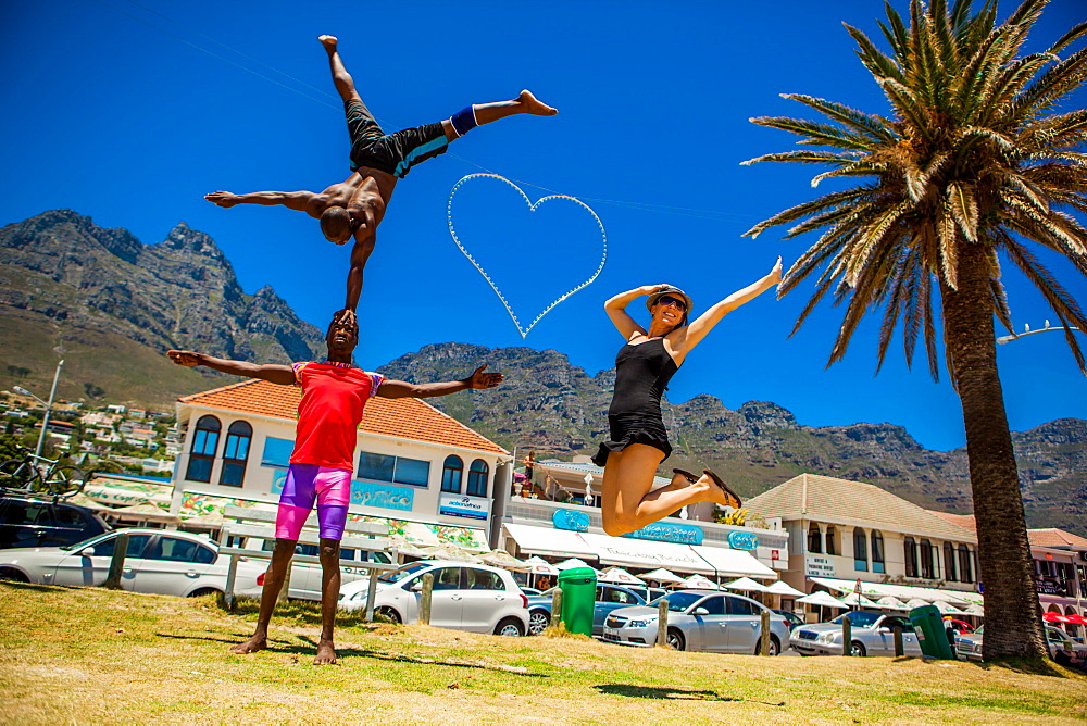 Laura Grier jumping with African acrobats, Camps Bay, South Africa, Africa