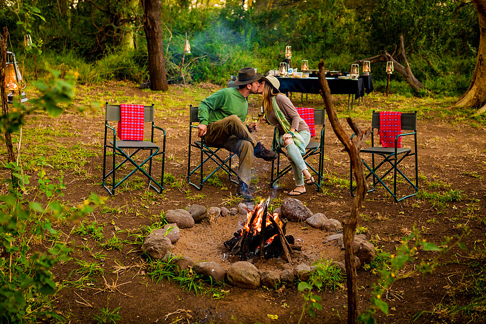 Couple kissing by a safari camp campfire in Zululand, South Africa, Africa