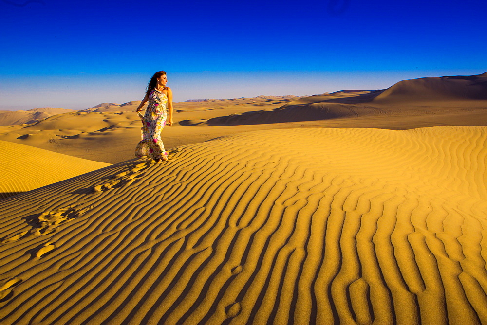 Girl standing on sand dunes at Huacachina Oasis, Peru, South America