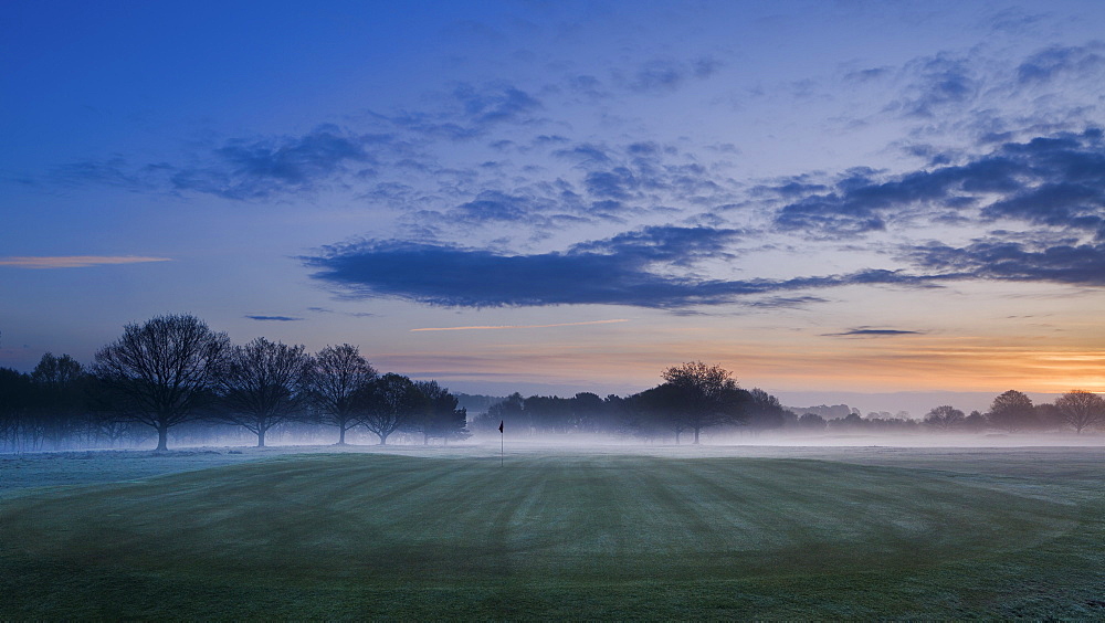 Dawn light seeps across the sky with mist lying across the landscape at Delamere Forest Golf Club, Cheshire, England, United Kingdom, Europe