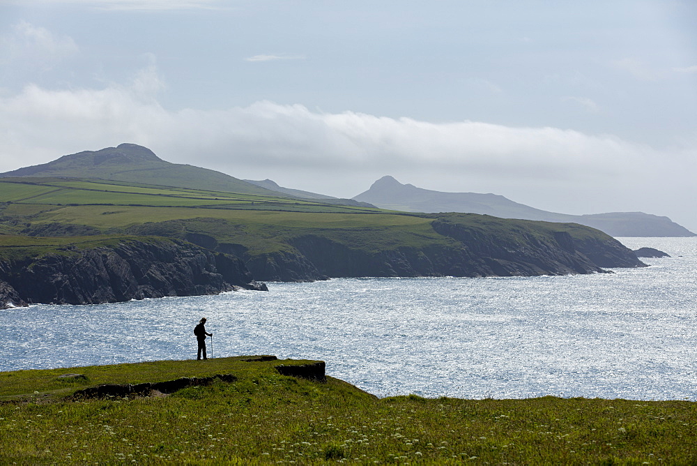 A walker enjoying a moments rest to admire the stunning views from the cliffs along the Pembrokeshire coast path, Wales, United Kingdom, Europe