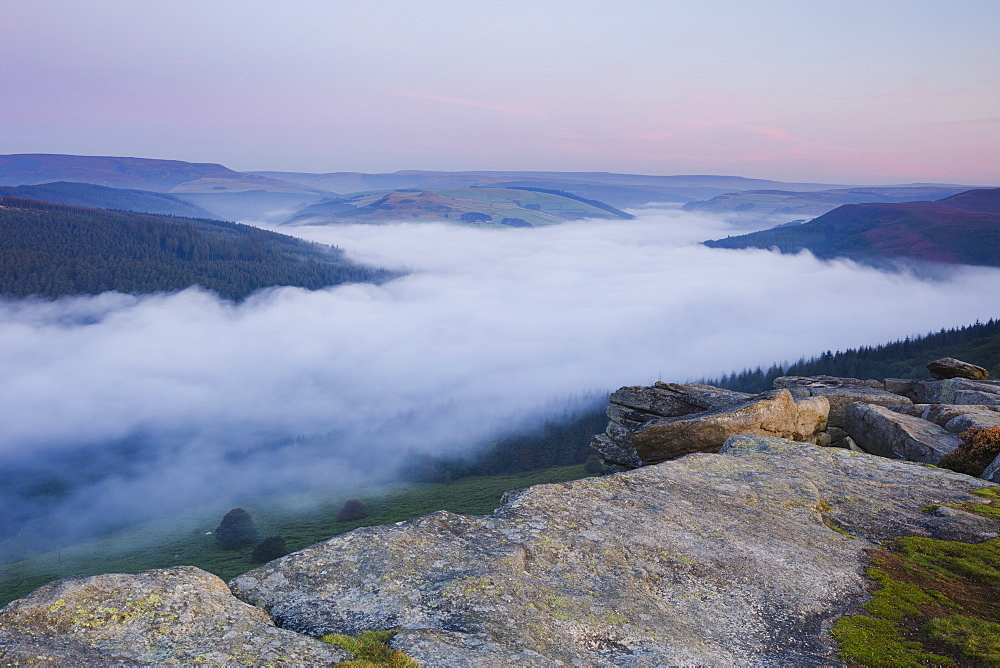 Dawn light breaks above the Peak District hills with a cloud inversion covering the Ladybower Reservoir below Bamford Edge, Peak District, Derbyshire, England, United Kingdom, Europe