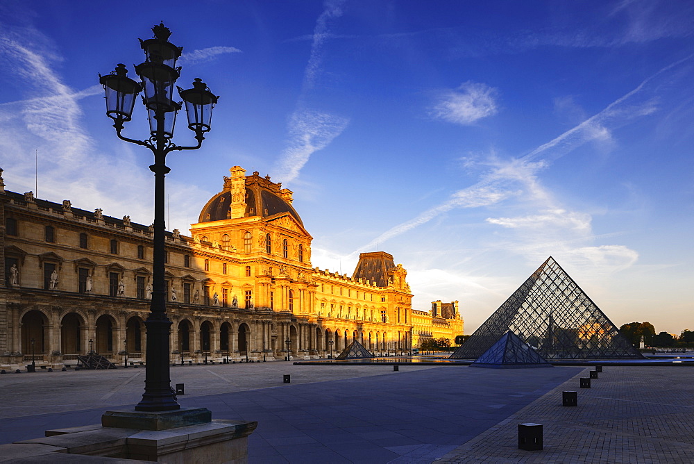 Dawn light illuminates the Louvre Palace bordering the Napoleon Courtyard and Louvre Pyramid, Paris, France, Europe