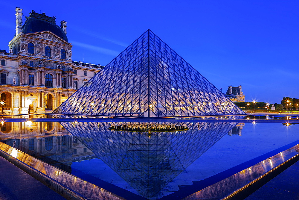 The Louvre Pyramid and Palace reflected in a still pool within the Napoleon Courtyard at twilight, Paris, France, Europe