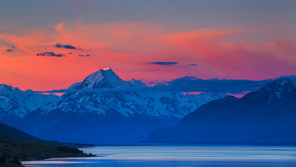 The last rays of the setting sun strike the peak of Aoraki (Mount Cook) beyond the shores of Lake Pukaki in the Southern Alps, UNESCO World Heritage Site, Canterbury, South Island, New Zealand, Pacific