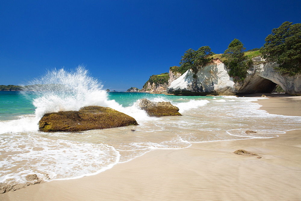 Waves splashing against large rocks on the beach in Cathedral Cove, Coromandel, Waikato, North Island, New Zealand, Pacific