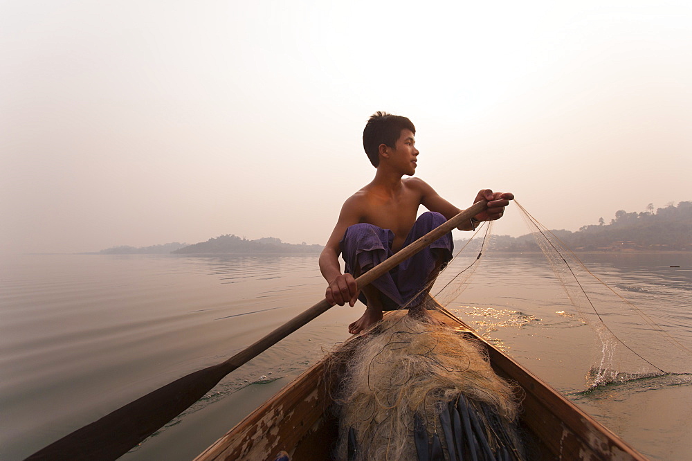 A young man pulls in his nets at the end of the day on Indawgyi Lake, Kachin State, Myanmar (Burma), Asia