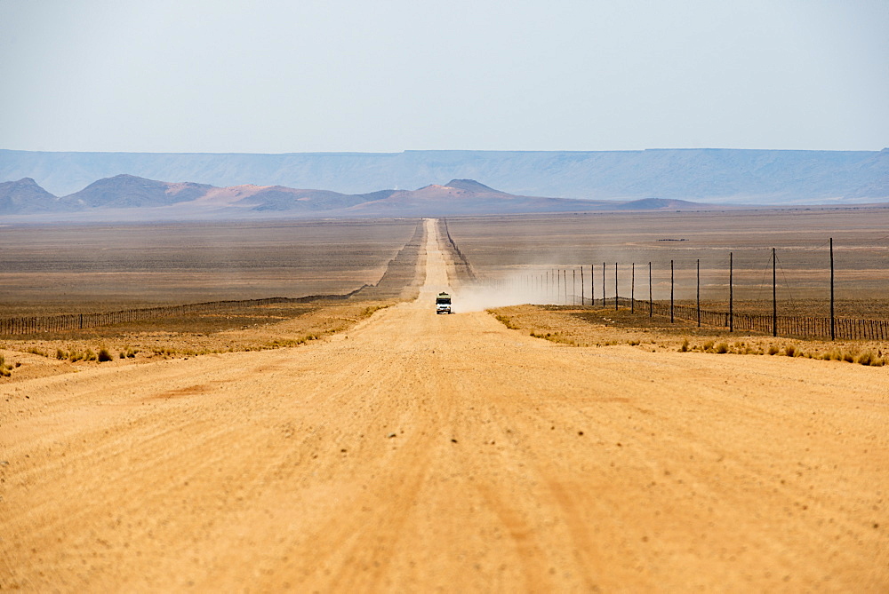 A jeep on a long sandy road in southern Namibia leaves a trail of dust, Namibia, Africa