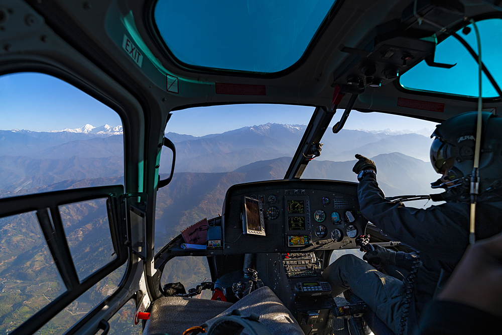 A helicopter flies towards the Himalayas as the pilot points towards the Ganesh Himal range through the window, Langtang region, Nepal, Asia