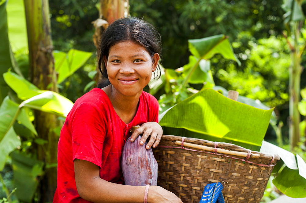 A Chakma girl in the Rangamati area in Bangladesh collects banana flowers which will be used to make curry, Chittagong Hill Tracts, Bangladesh, Asia