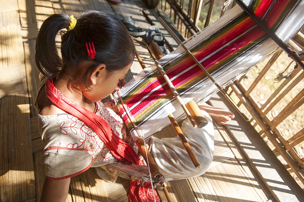 A little girl learns the art of weaving on a hand loom, Chittangong Hill Tracts region, Bangladesh, Asia